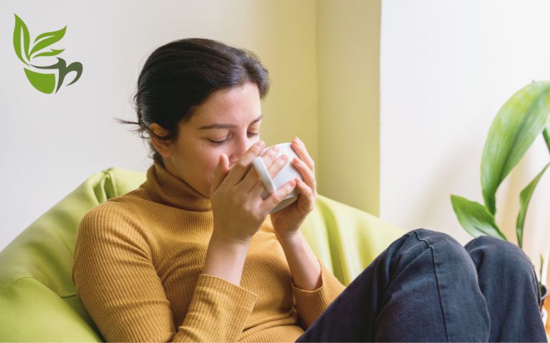 immagine di una ragazza seduta sul divano con una tisana per rilassarsi di natura da bere